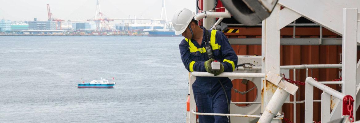 A man in a white hard hat with a controller in his hand looking down