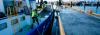 A seafarer handling ropes on a boat next to a jetty